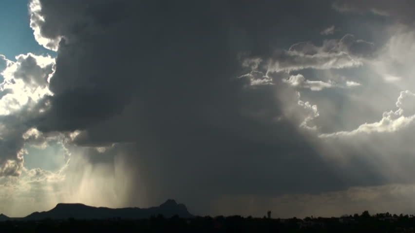Ominous dark rain cloud sweeps over mountain range, dumps rain, followed by blue, sunlit skies. 1920x1080