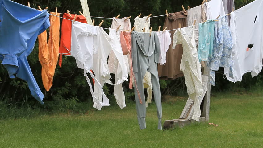 Laundry blowing in the wind on an old fashion clothes line. Old antique style clothing including long johns, apron, and linen clothes. Wind blowing.