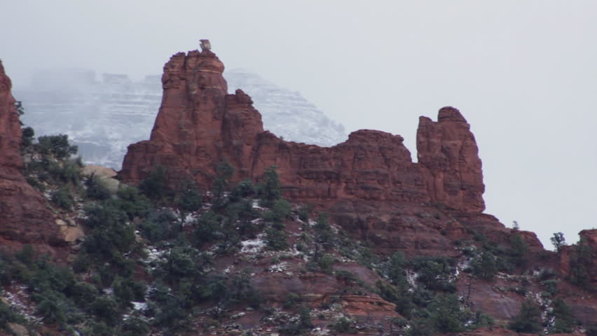 A cold autumn morning and the beauty of the red rocks of Sedona, Arizona under a light dusting of snow from the first snow of the season as clouds move gently by in the background.