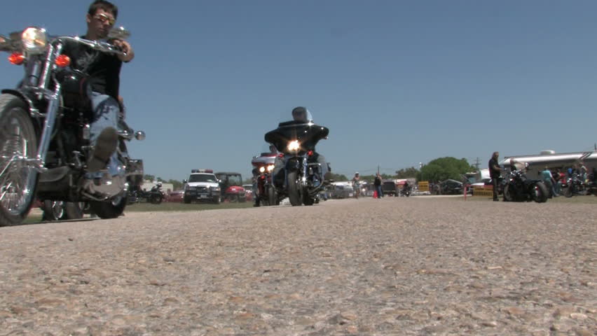 Motorcycles at a rally in south Texas. Low angle with bikes and riders passing as they ride forwards from the entrance gate.