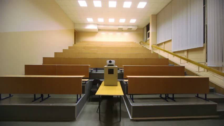 Light turned off, and then switched on, in empty lecture auditorium, white projector and wooden furniture on several levels