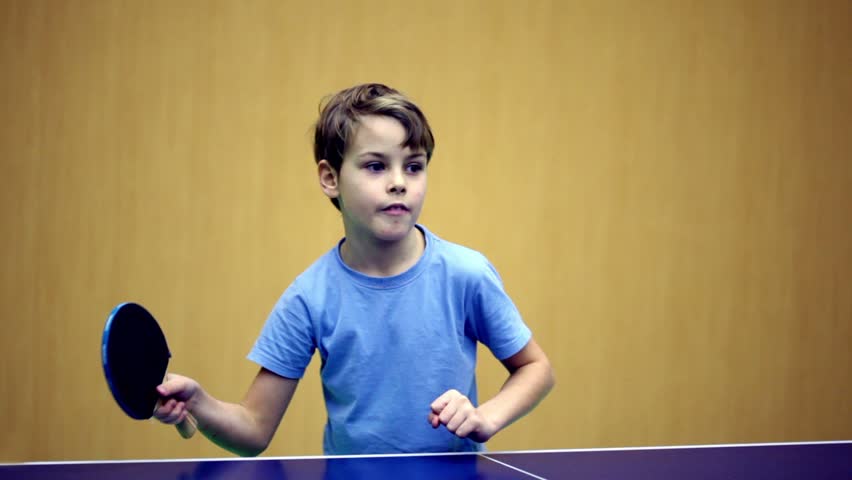 Little boy wearing blue shirt playing ping pong, he got concentrated face 