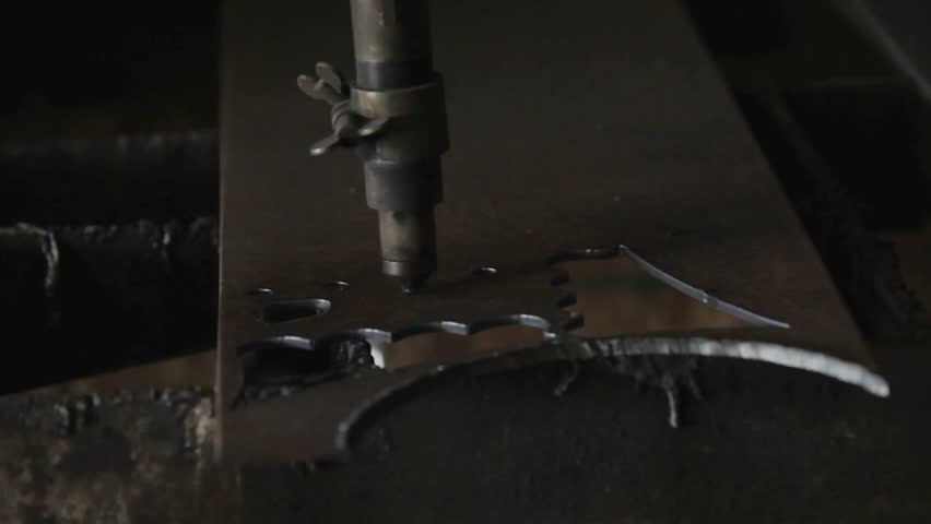 Plasma cutter slicing through hard steel plate. Cutting a decoration or part used in industry. Sparks and molten metal from automatic machine. Industrial equipment.