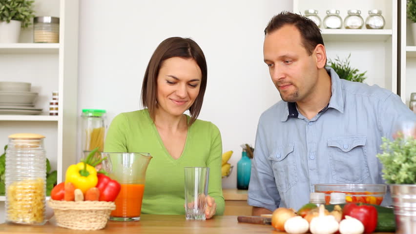 Happy couple drinking fresh healthy juice in the kitchen 