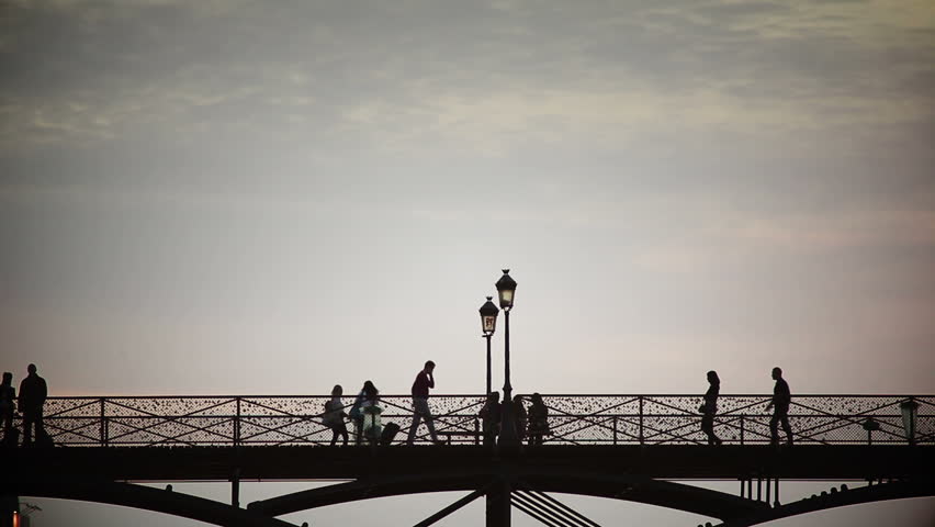 People walk along Ponts des Arts bridge which is covered in love locks