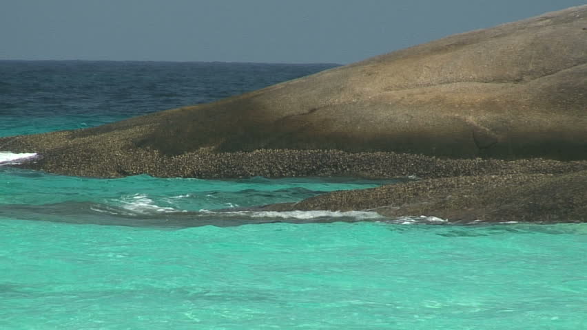 Rock shore slopes into tropical water