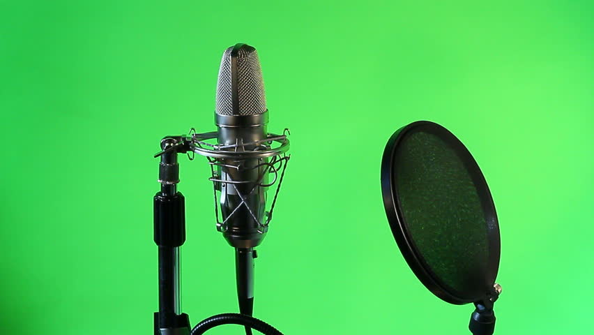 A closeup view of a vocal condenser mic with wind screen. Green screen background.