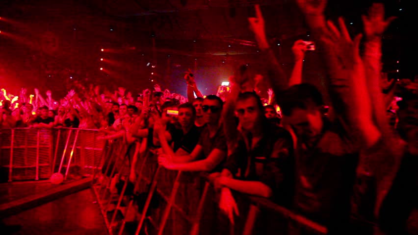 MOSCOW - MAY 6: Spectators stand behind fencing at rave party with red illumination during Armin Only show on May 6, 2011 in Moscow, Russia.