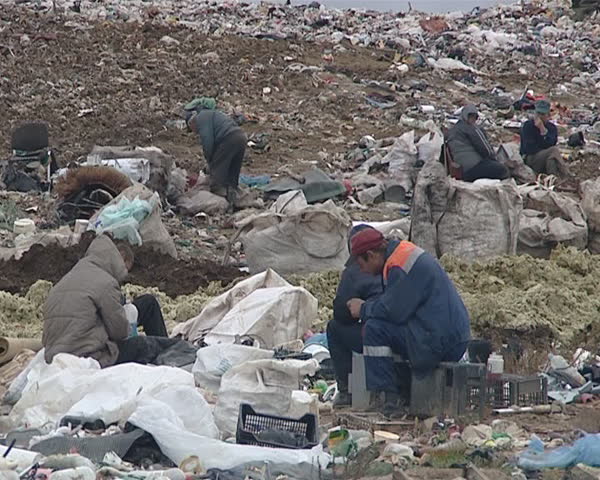 Dirty deprived homeless people and mountains of garbage in dump. Fight for survival. Environmental pollution. Poverty. 