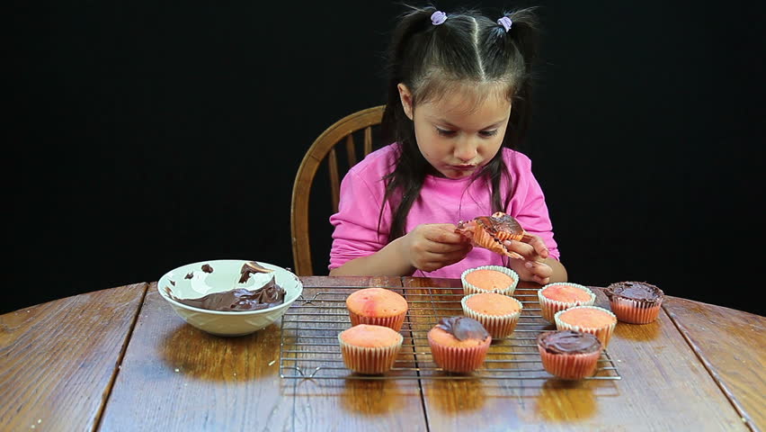 Little girl eating yummy homemade cupcakes at kitchen table - HD - 1920x1080