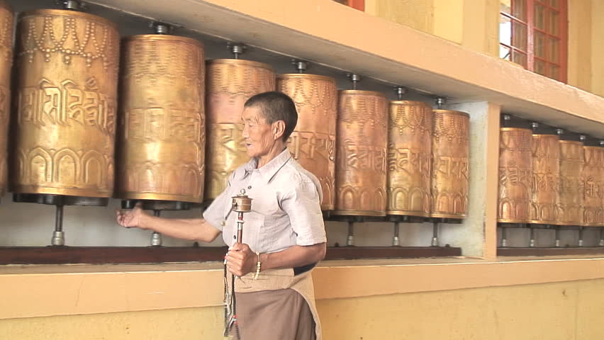 MCLEOD GANJ, INDIA - AUGUST 24, 2006: Tibetan nun spins prayer wheels