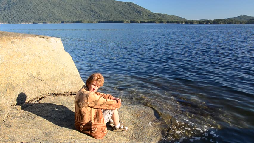 woman sitting at the rock at sunny day over nice ocean view