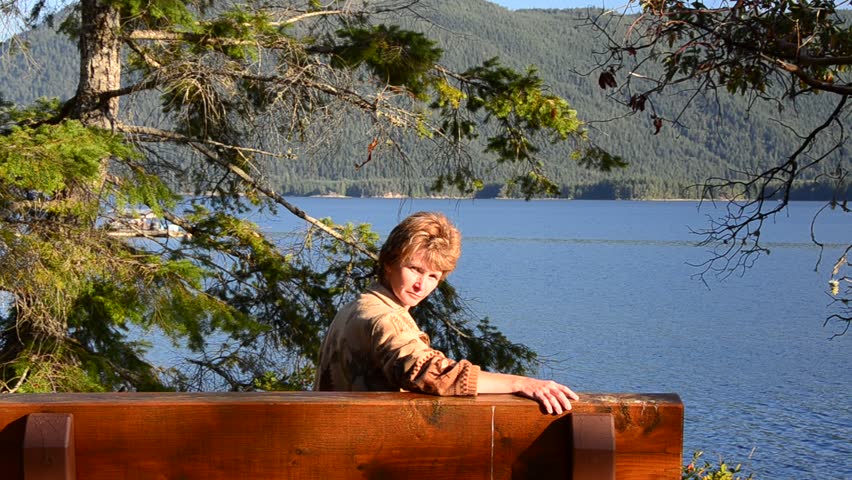 woman sitting at the picnic bench at sunny day over nice ocean view