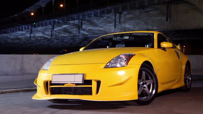 Yellow sport car stand at background of bridge at night