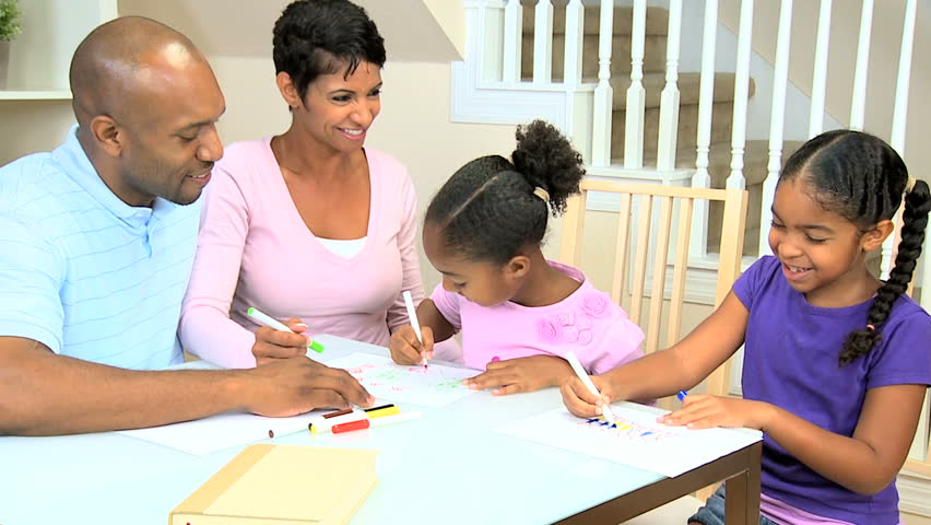 Young ethnic parents watching their young daughters using coloring crayons