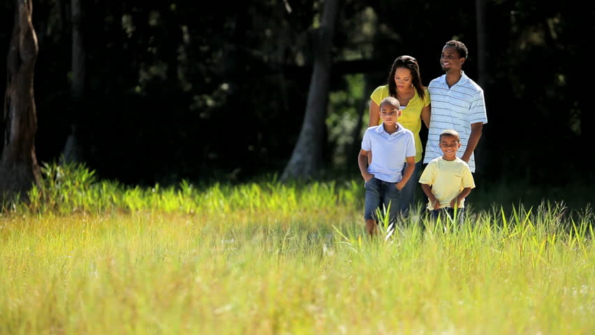 Young african american family walking together through parkland