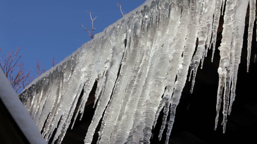 Icicles hanging from roof begin to melt with the coming of spring. Closeup.