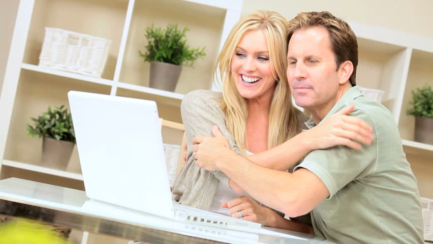 Young caucasian couple with laptop excited to see the results of their online success