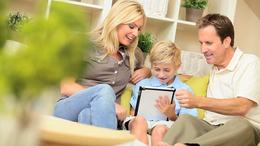Happy caucasian family relaxing on home sofa using a modern wireless tablet