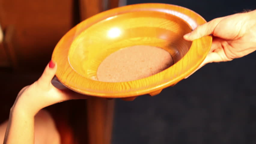 Person giving coins into the offering plate.