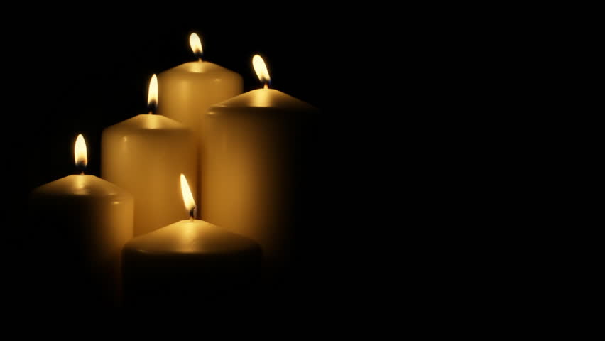 Five flickering candles on the black background