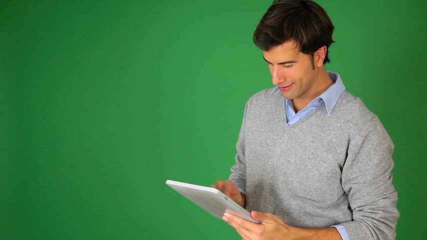 Young man standing on green background with tablet