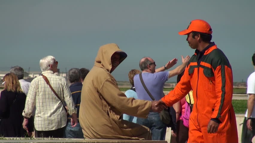 CASABLANCA - MARCH 12: A maintenance work operator greets a hooded man and, with a workmate, mingles with a multi-ethnic crowd on the square by Hassan II Mosque on March 12, 2011 in Casablanca, Morocco.