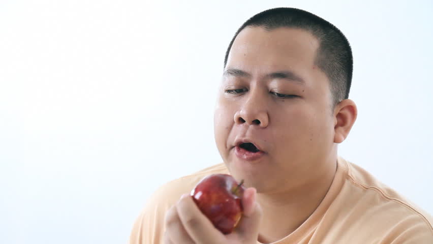 Fat young man eating an apple. Diet concept.