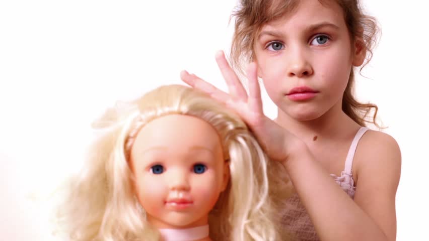 Little girl plays with dolls hairdo, isolated on white background