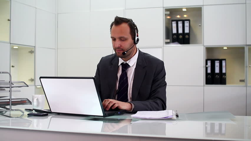 Young helpdesk consultant talking on headset in modern office