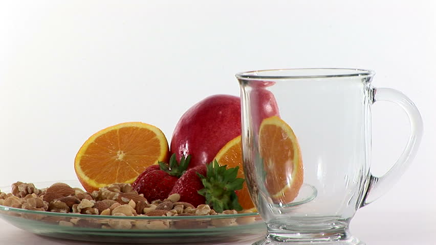 Brewing a cup of green tea with nuts and fruits placed near by. 