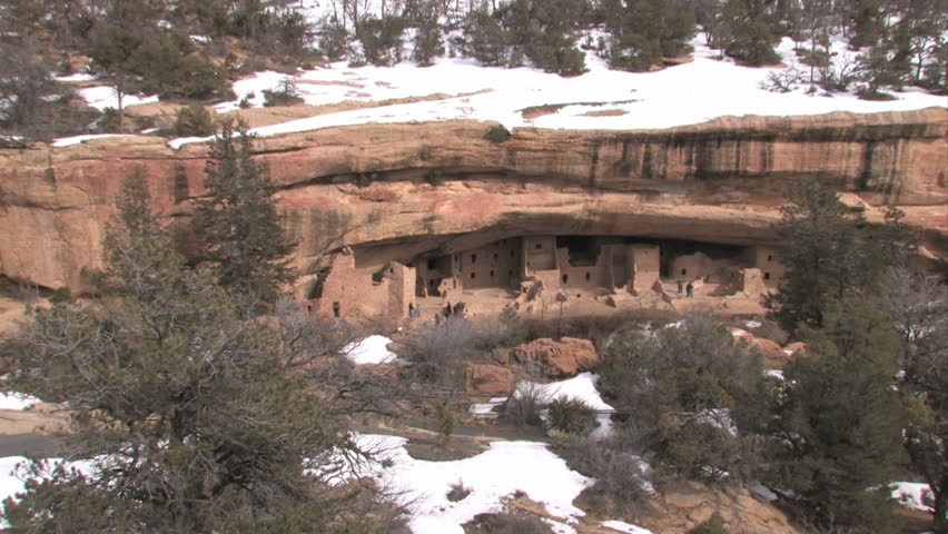Mesa Verde National park in southern Colorado. Spruce Tree ruins. Park ranger and tourists exploring.  Sheer cliff overhanging rocks.  Historic Native American homeland and heritage. Zoom.