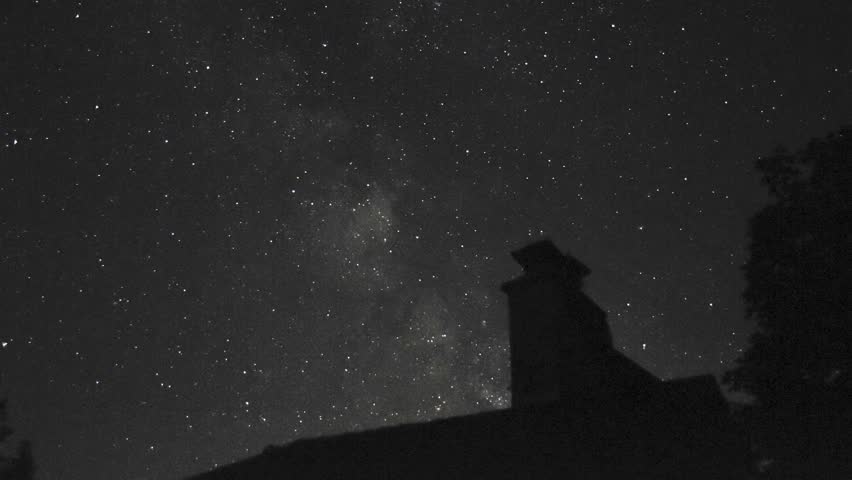 timelapse of the milky way traveling across the sky above a house roof and chimney