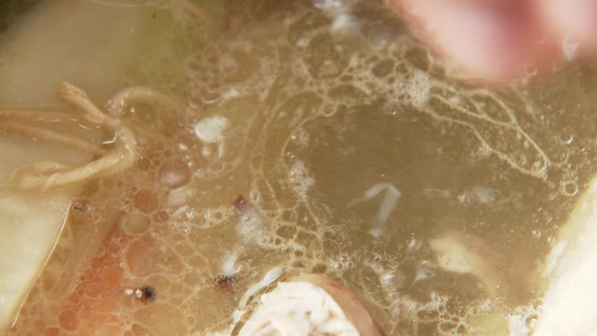 Juniper berries and salt being added to chicken soup