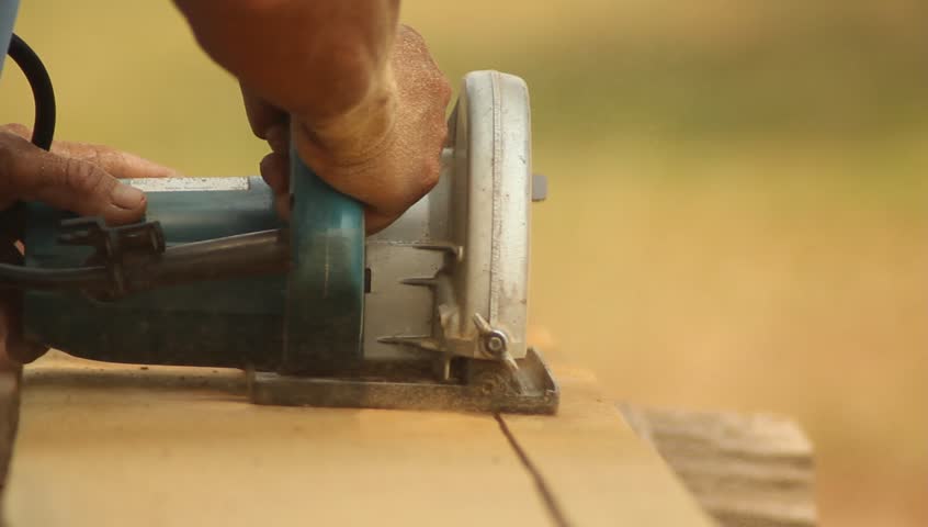 Handyman cutting wooden floor with Electric saws