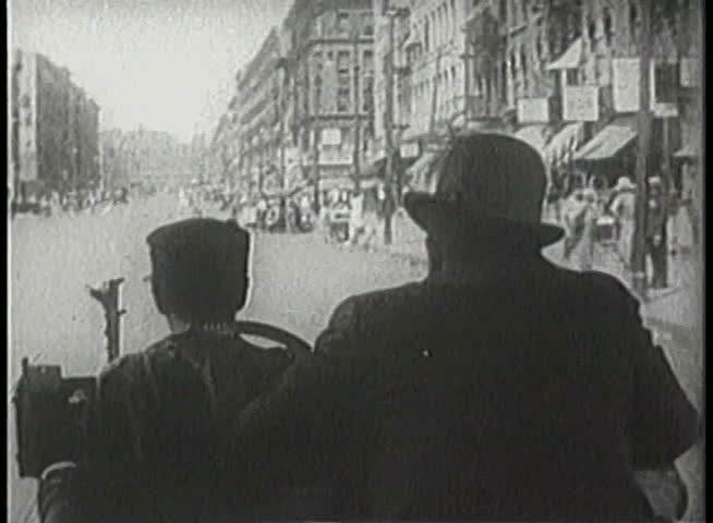 Over-the-shoulder shot of cab driver and passenger riding on crowded street