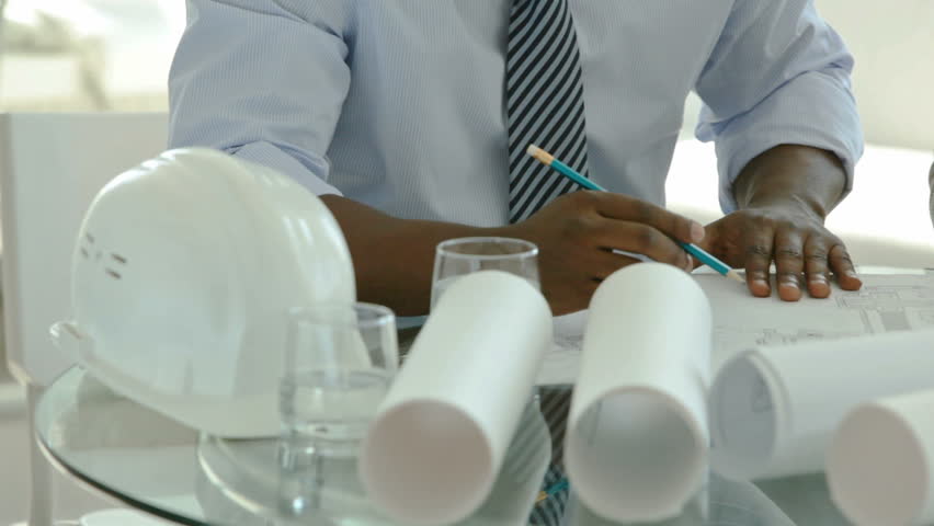 Dolly shot of business people drawing blueprints