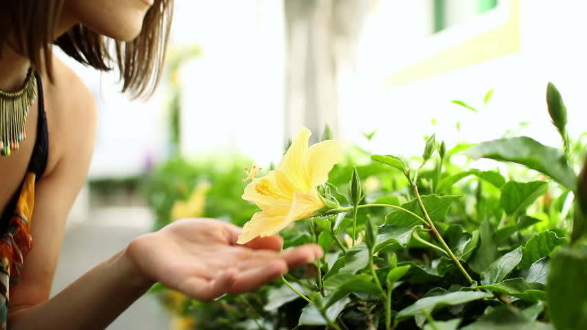 Young happy woman smelling yellow flower 