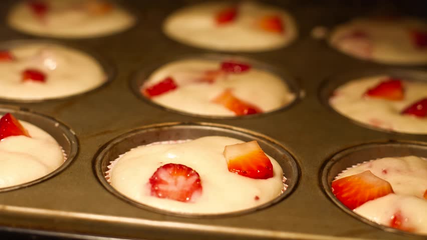 Homemade strawberry muffins in oven, shallow DOF, time lapse