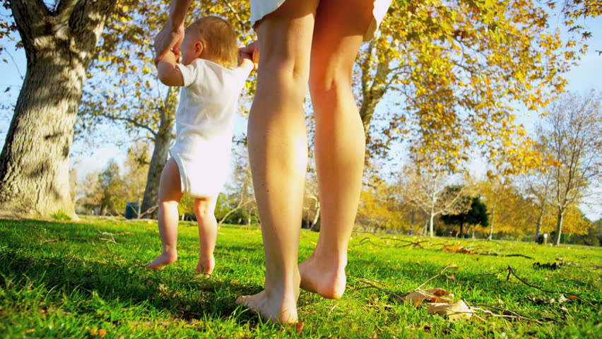 Caucasian mother supporting her little baby practicing his first steps