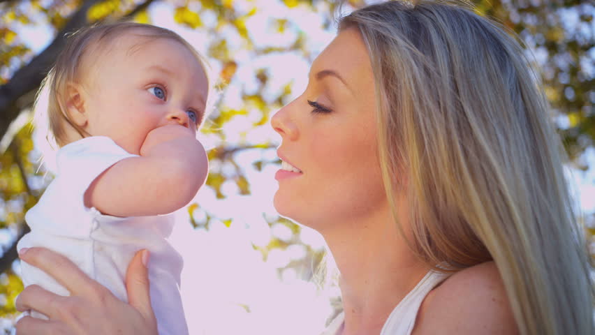 Close up of blonde young mother outdoors tenderly holding her young child