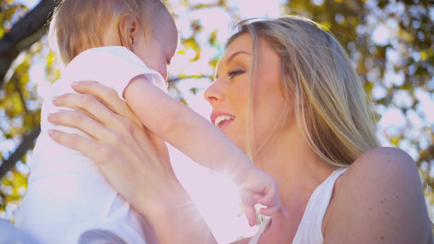 Beautiful loving young mother outdoors holding her young child
