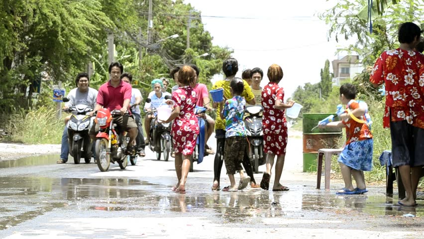BANGKOK - APRIL 13: Children enjoying the annual Songkran festivities with a water fight involving children and a passing gang of motorbikes on April 13, 2012 in Bangkok, Thailand.