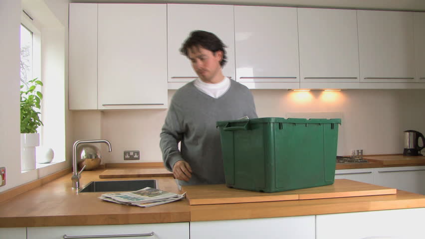 MEDIUM SHOT PAN OF A MAN RECYCLING NEWSPAPER