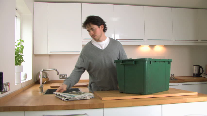 MEDIUM SHOT PAN OF A MAN RECYCLING NEWSPAPER