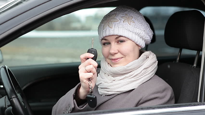 Young beautiful Caucasian woman showing ignition key and inserting it