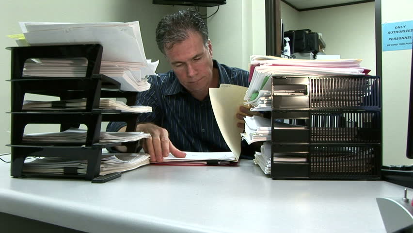 A man at his desk showing signs of being overworked