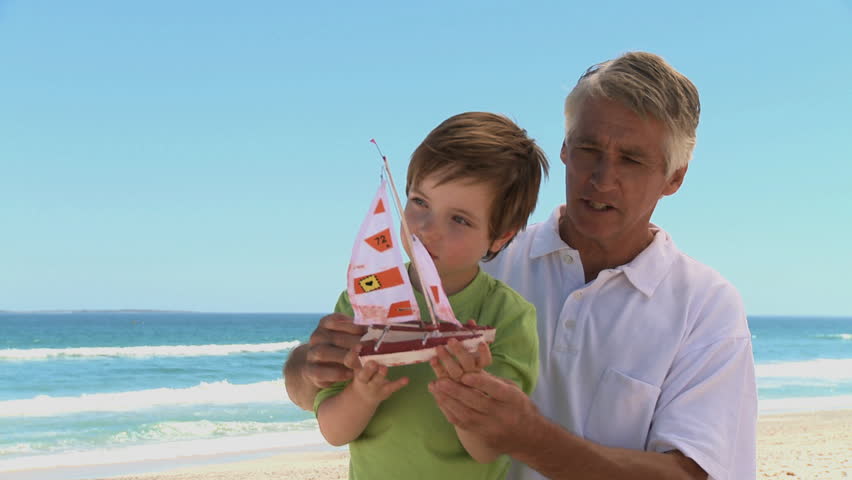 MEDIUM SHOT OF A GRANDFATHER AND GRANDSON PLAYING WITH A TOY BOAT