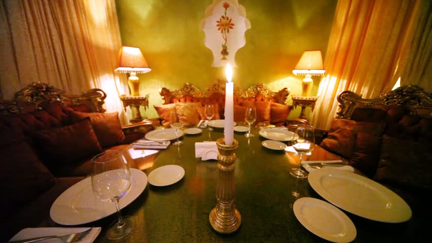Burning candle stands on decorated table among subjects of east decor