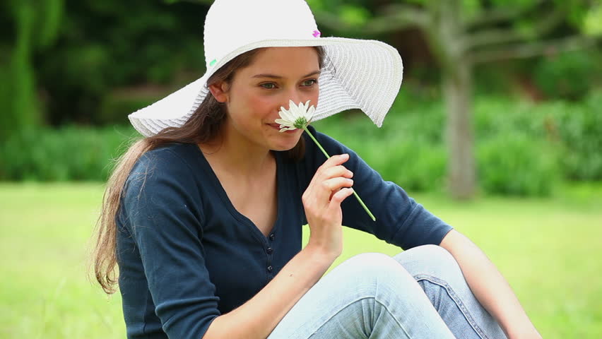 Happy woman smelling a white flower in a park